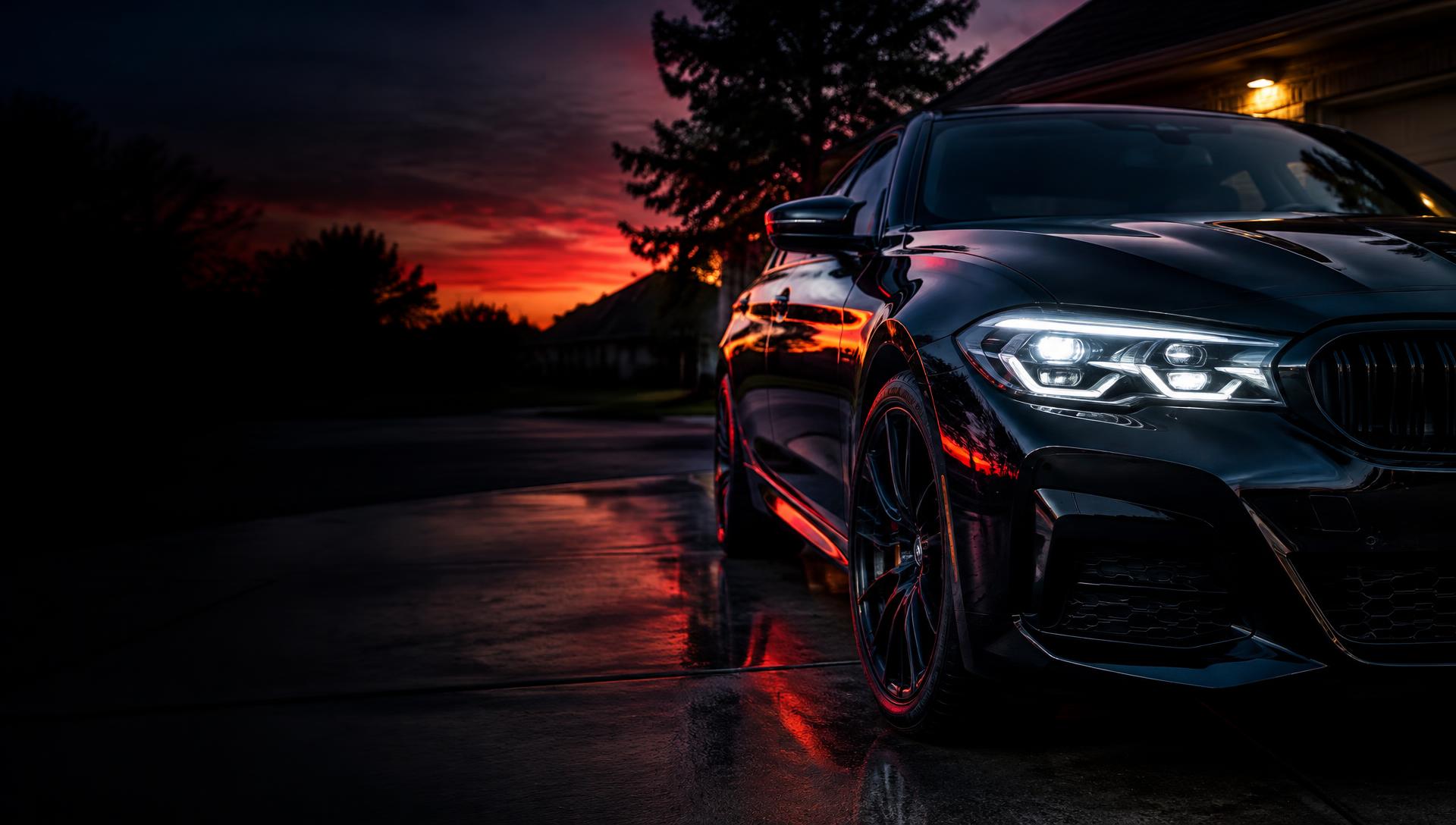 Black sedan with brilliantly clear headlights in a driveway